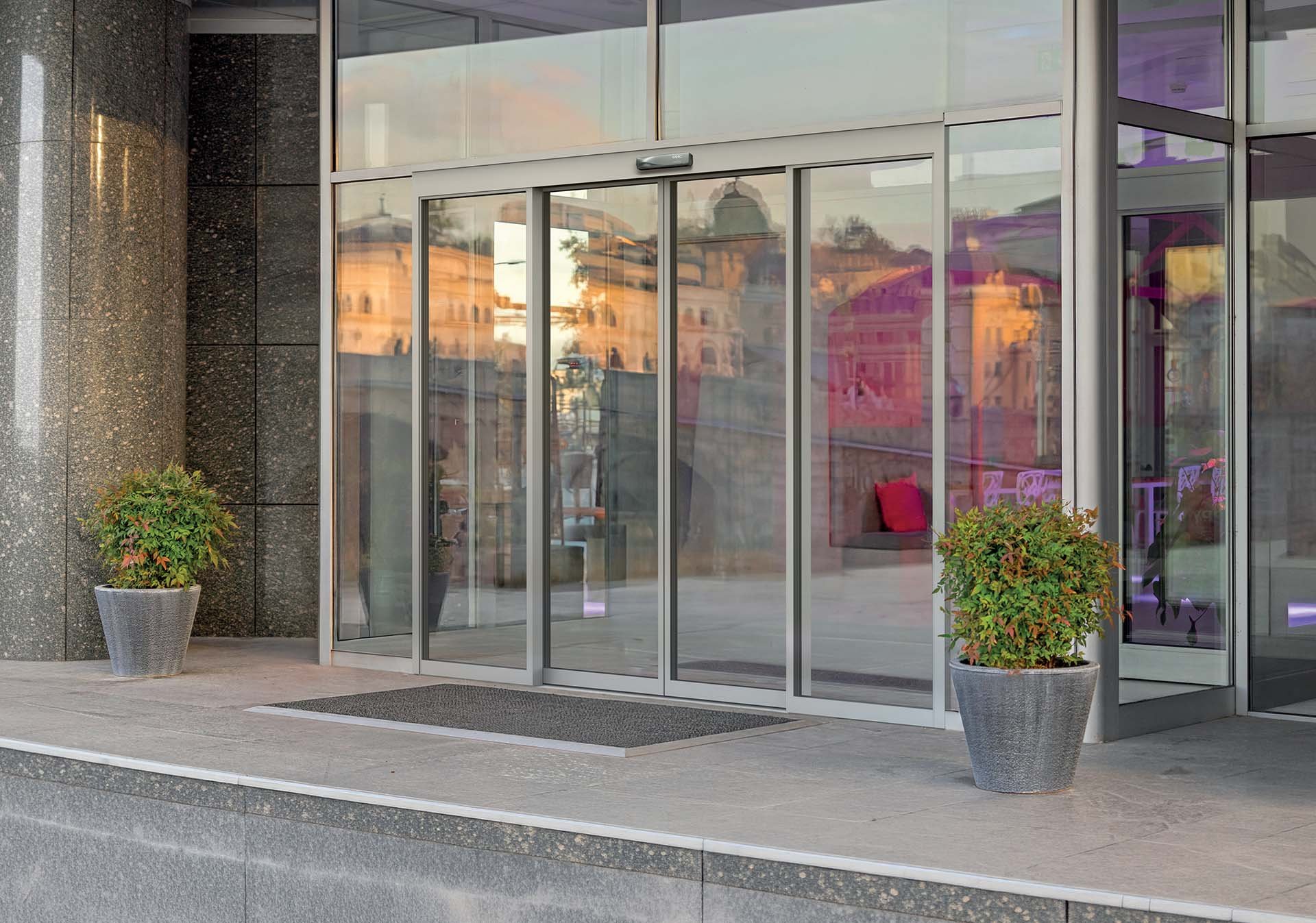 FAAC TK50 THERM automatic sliding entrance in a stone-clad building facade