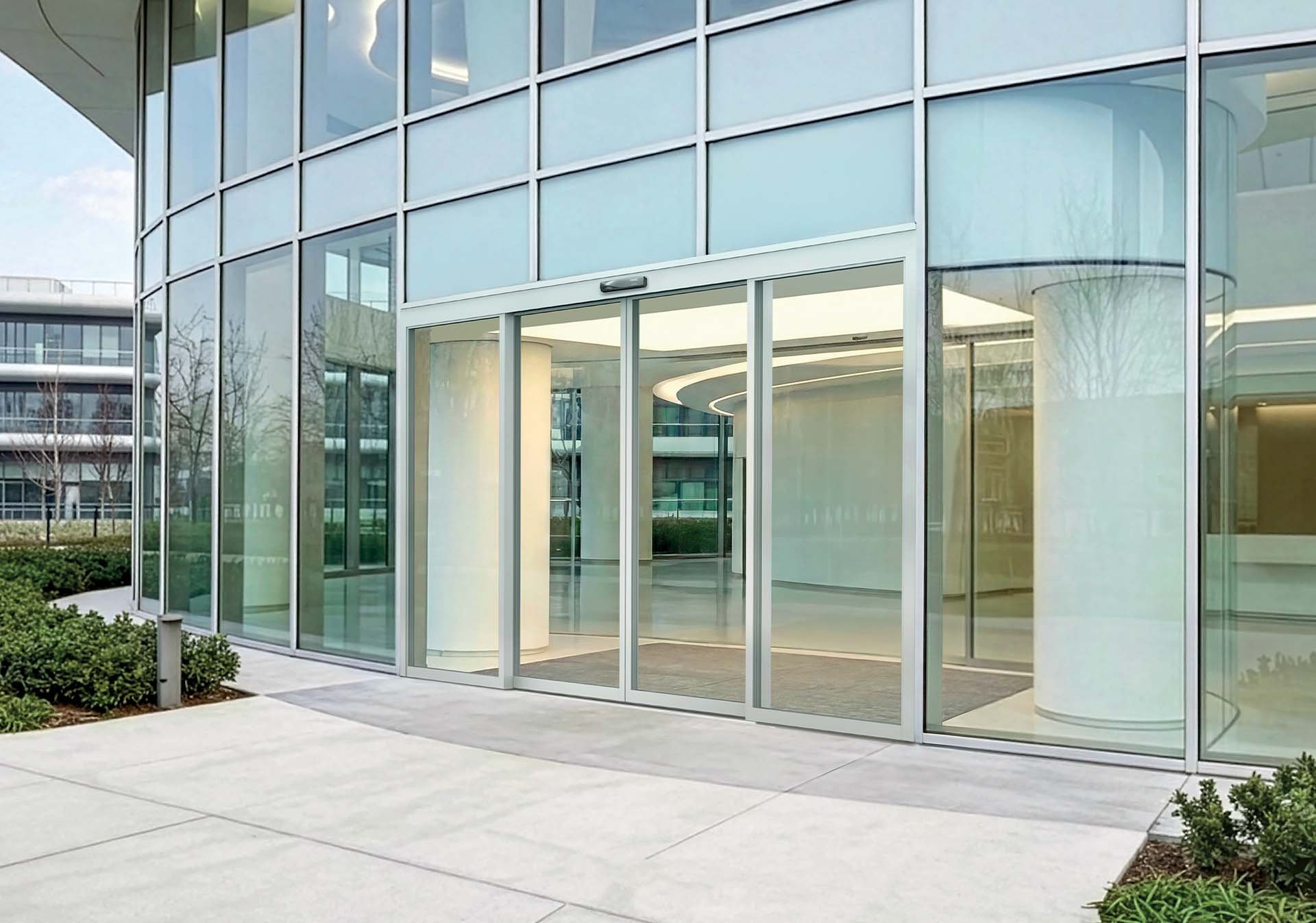 FAAC TK50 THERM thermally broken sliding entrance in the curved glass facade of a contemporary building